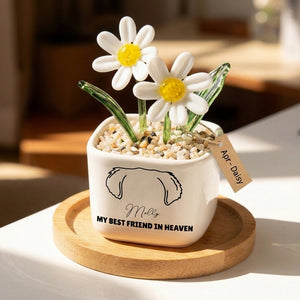 Decorative pot with artificial flowers and a tag on a wooden coaster