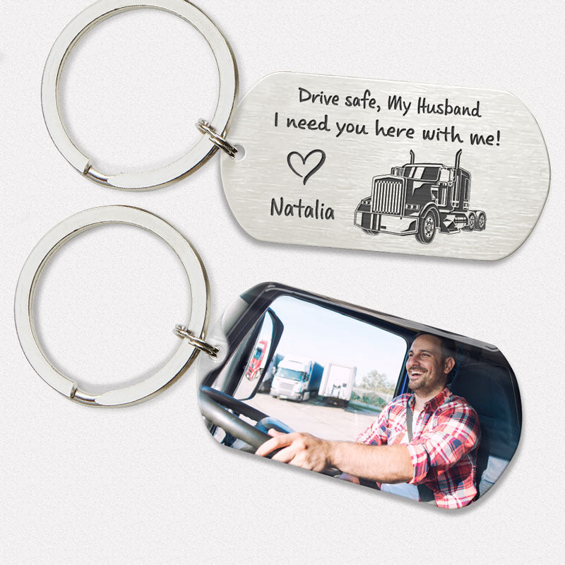 Two keychains, one with an engraved message 'Drive safe, My Husband I need you here with me! - Natalia' and a semi-truck image, and the other with a custom photo of a smiling man inside a car.