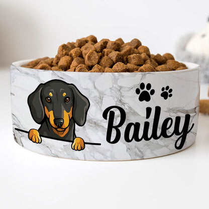 Custom ceramic dog bowl with a grey marble pattern, featuring a personalized name 'Bailey' in cursive script, and an illustration of a dog's face and paw prints in black.