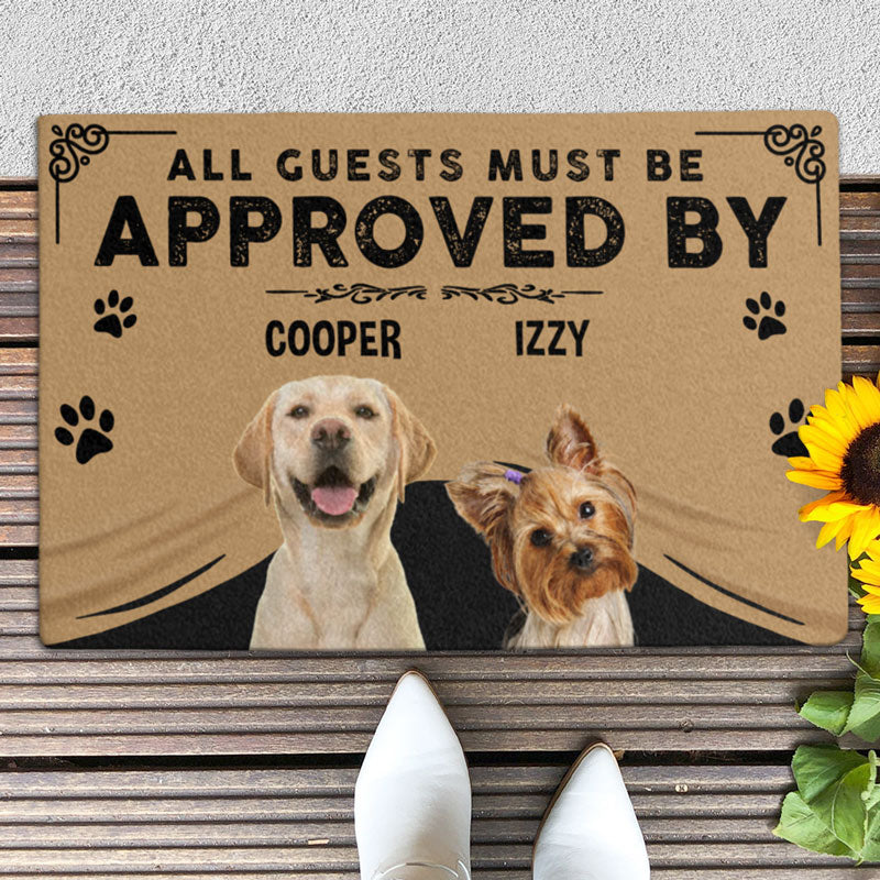 Customized doormat with the text 'All guests must be approved by' followed by two dog names 'Cooper' and 'Izzy', along with images of two dogs, a golden retriever and a yorkshire terrier, on a front porch.